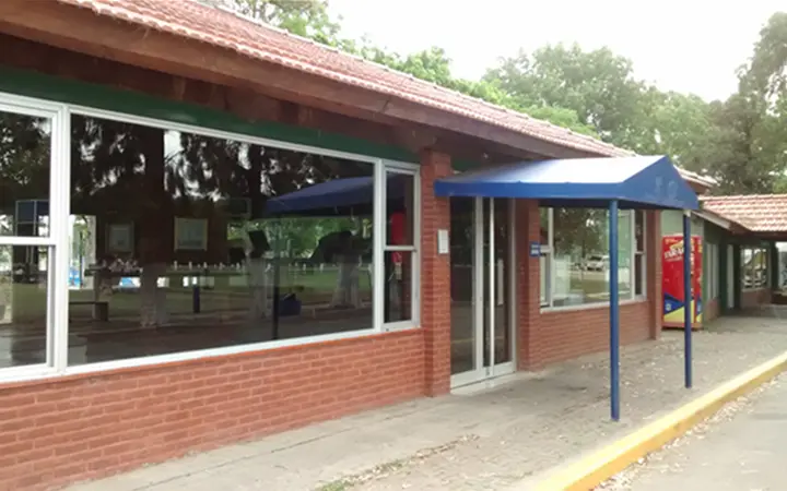 Edificio de ladrillo de la sede, con ventanales y un toldo azul en la entrada
